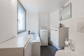A modern bathroom with a toilet, sink, and shower area. - Le Bain Finkwiller - Parking inclus (Strasbourg)