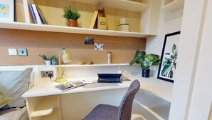 Ein moderner Arbeitsraum mit Schreibtisch, Stuhl, Regalen mit Büchern und Pflanzen sowie einer Korkwand.