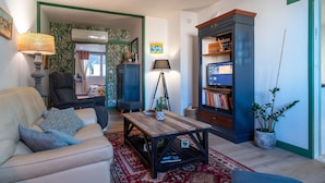 Sala de estar con sofá, mesa de centro, estantería y objetos decorativos.