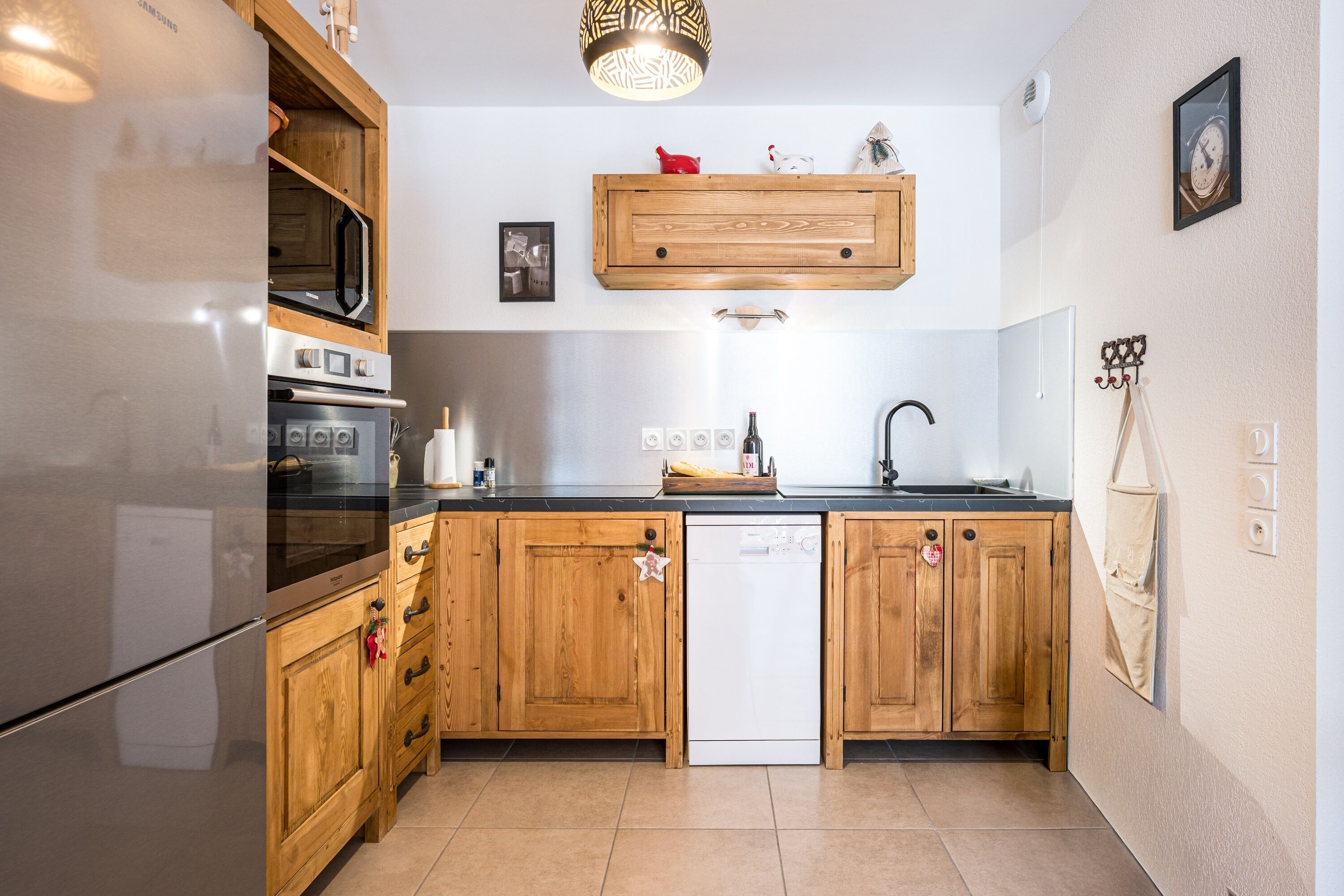 Cocina con armarios de madera, refrigerador de acero inoxidable, lavavajillas y encimera de madera.