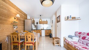 Een compacte leefruimte met een eethoek, kitchenette en een zithoek.
