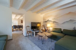 Ein Wohnzimmer mit Fernseher, Couchtisch aus Holz und einer Couch.