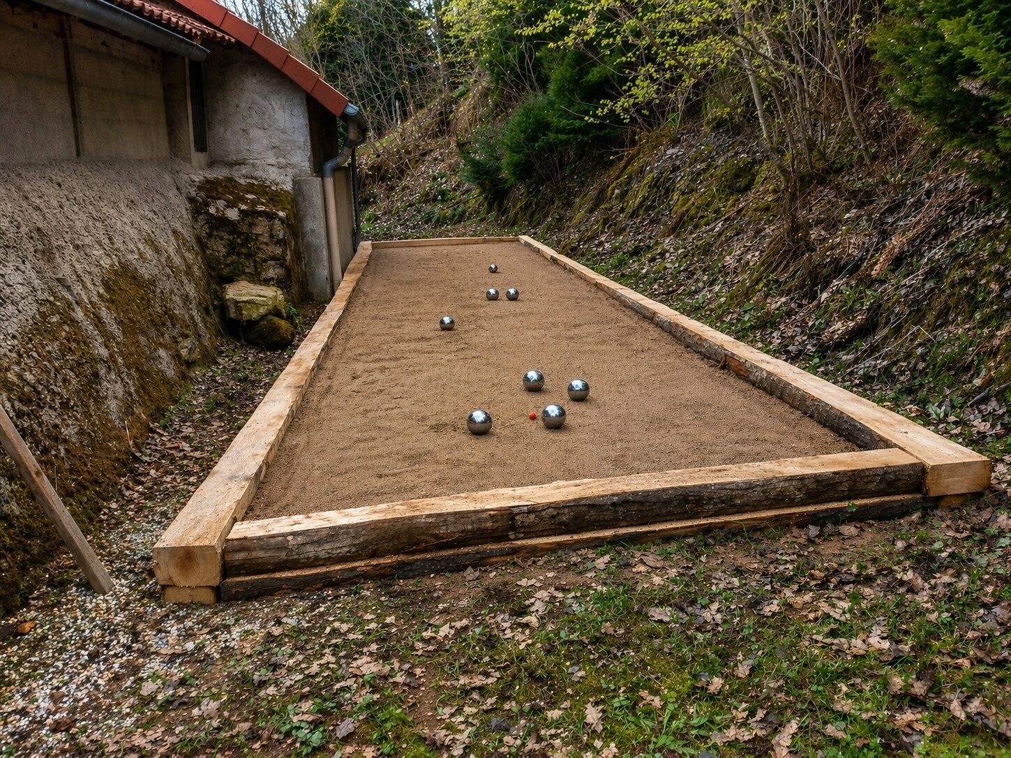 A shuffleboard table with balls, a wooden border, and a stone wall in the background.