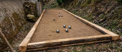 A shuffleboard table with balls, a wooden border, and a stone wall in the background.