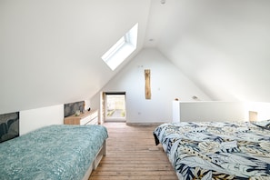 A bedroom with two beds, a skylight, wooden flooring, and a view to the outside. - Le Lotus - 1000 m² de jardin (Putanges-le-Lac)