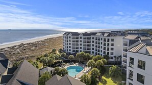 Un hôtel doté d’une piscine, entouré de palmiers et offrant une vue sur la plage et l’océan.