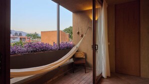 Een balkon met een hangmat, een stoel en uitzicht op gebouwen en bloemen.
