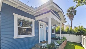 A blue house with a porch, a front door, and a small garden area with plants.