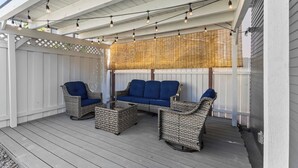 An outdoor patio with wicker furniture and string lights.