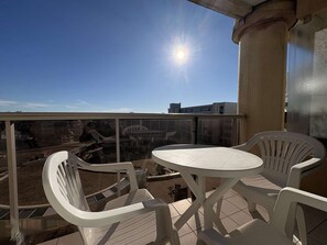 A balcony with a round table and two chairs, overlooking a cityscape with buildings and a bridge. - PORNICHET - QUARTIER DES OCEANES (PORNICHET)