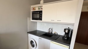Eine kleine Küche mit Mikrowelle, Kaffeemaschine und Waschmaschine.