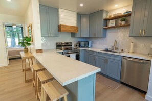 Une cuisine moderne avec des meubles de couleur bleu clair, des appareils en acier inoxydable et des tabourets en bois.