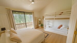 A bedroom with a large bed, a bunk bed, wooden flooring, a ceiling fan, and a window with curtains. - Spacious 4-bedroom condo in gorgeous Kahuku with AC (Kahuku)