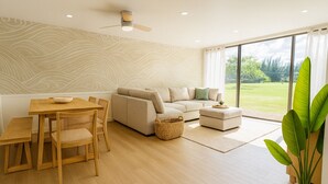 A modern living room with a sofa, ottoman, dining table, and chairs. - Spacious 4-bedroom condo in gorgeous Kahuku with AC (Kahuku)