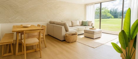 A modern living room with a sofa, ottoman, dining table, and chairs.