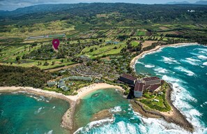 An aerial view of a coastal resort with beachfront properties, a golf course, and a large building likely serving as the main hotel. - Royal Turtle Palms: Luxe 4BR Turtle Bay Condo, Sleeps 12 (Kahuku)