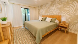 A bedroom with a bed, bedside table, lamp, and a view of the outdoors through a window. - Spacious 4-bedroom condo in gorgeous Kahuku with AC (Kahuku)