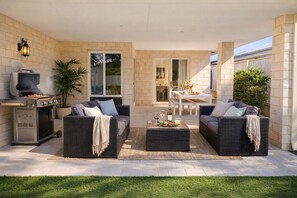 An outdoor patio with two wicker sofas, a dining table, and a grill. - Coastal retreat 2km from the beach (Golden Bay)