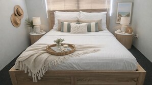A neatly made bed with a wooden frame, white bedding, and a decorative tray with a candle and seashells. - Coastal retreat 2km from the beach (Golden Bay)