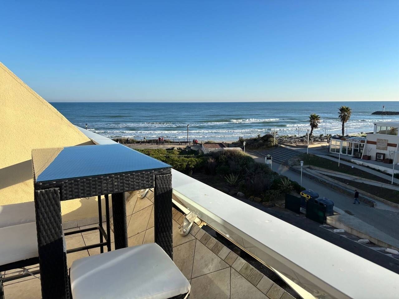 Un balcone con vista sull'oceano, il ristorante Horizon e una palma.