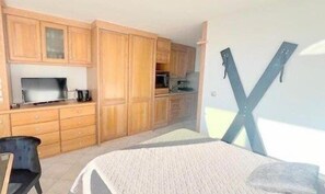 Een kamer met houten kastjes, een bed en een groot raam.