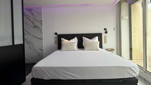 Een moderne slaapkamer met een groot bed, marmeren wanden en uitzicht door een glazen deur.