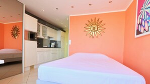 Quarto com cama, cozinha compacta e banheiro.