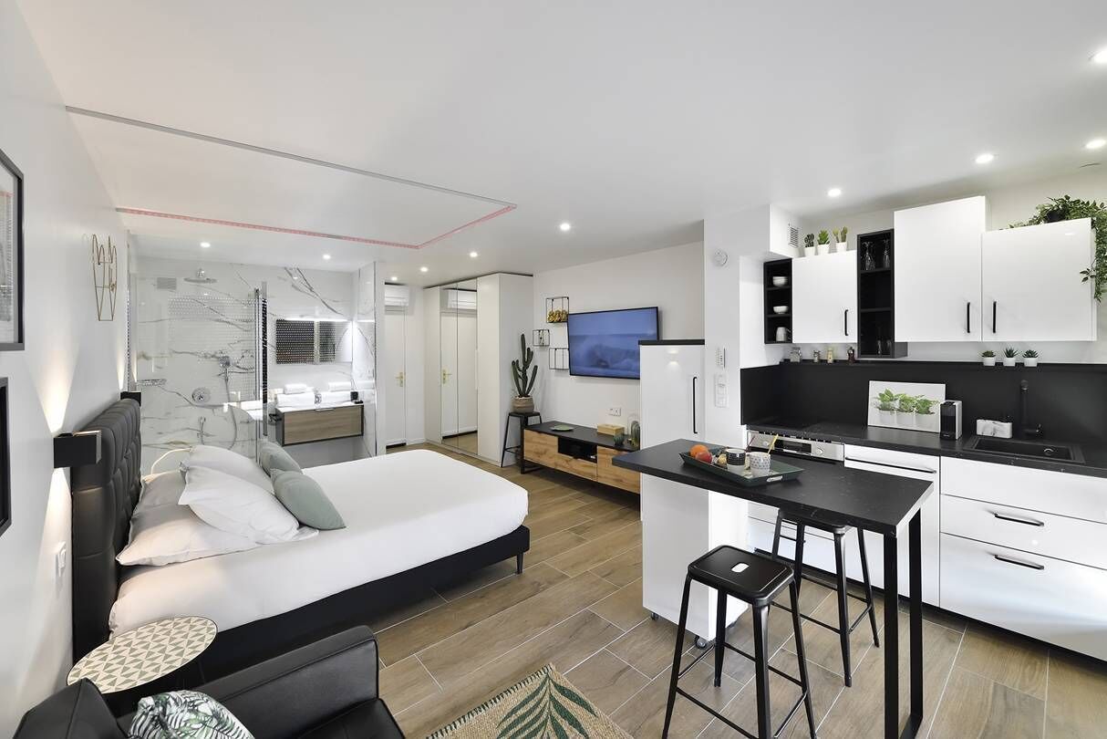 Ein modernes Hotelzimmer mit Bett, einer kleinen Sitzecke, einer Küchenzeile und einem Badezimmer.