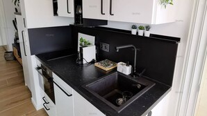 Uma cozinha moderna com armários brancos, bancada preta e pia preta.