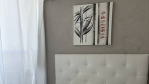 A neatly made bed with a tufted headboard, white bedding, and two pieces of wall art depicting abstract plant designs. - BROWN - Studio Héliopolis D 29 - Luxury - 2 people (AGDE)