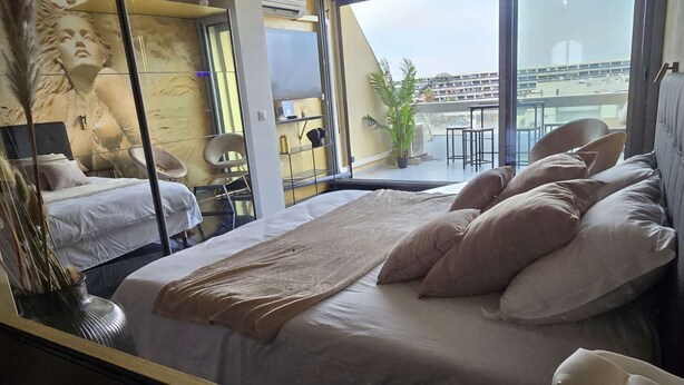 Una habitación de hotel moderna con una cama grande, vistas de la ciudad y un mural en la pared.
