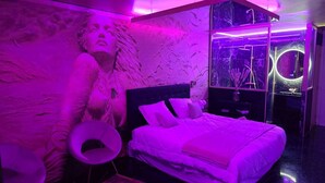 Un dormitorio moderno con una cama grande, un tocador y una pieza de arte original en la pared.