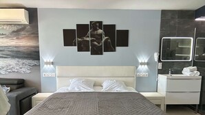 Una camera d'albergo moderna con un letto grande, un comodino, una cassettiera e uno specchio fissato alla parete.
