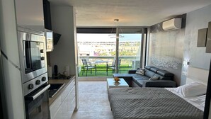 Un appartamento moderno con angolo cottura, un letto, un divano e un balcone con vista sugli edifici.