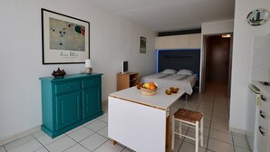 A compact bedroom with a bed, bedside table, and a small desk. - Studio Héliopolis D 51 - 4 people (AGDE)