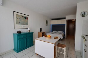 A compact bedroom with a bed, bedside table, and a small desk. - Studio Héliopolis D 51 - 4 people (AGDE)