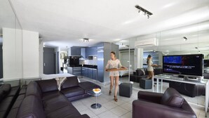 Un salon moderne avec un canapé, une table basse et un téléviseur.