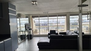 Un salon moderne avec une grande fenêtre, un canapé et un téléviseur à écran plat.