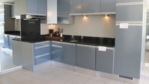 Une cuisine moderne avec des meubles gris, un plan de travail noir et un évier en acier inoxydable.