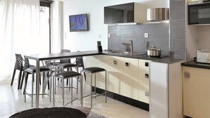 Cozinha moderna com ilha central, banquetas e mesa de jantar com cadeiras.