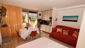 Une chambre d’hôtel compacte comprenant un coin repas, un canapé rouge et un tableau accroché au mur.