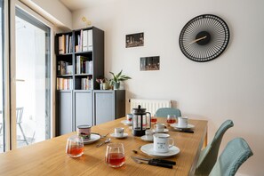 A dining area with a wooden table set for tea, a bookshelf, and a cityscape wall clock. - Appartement Seguin - Welkeys (Boulogne-Billancourt)
