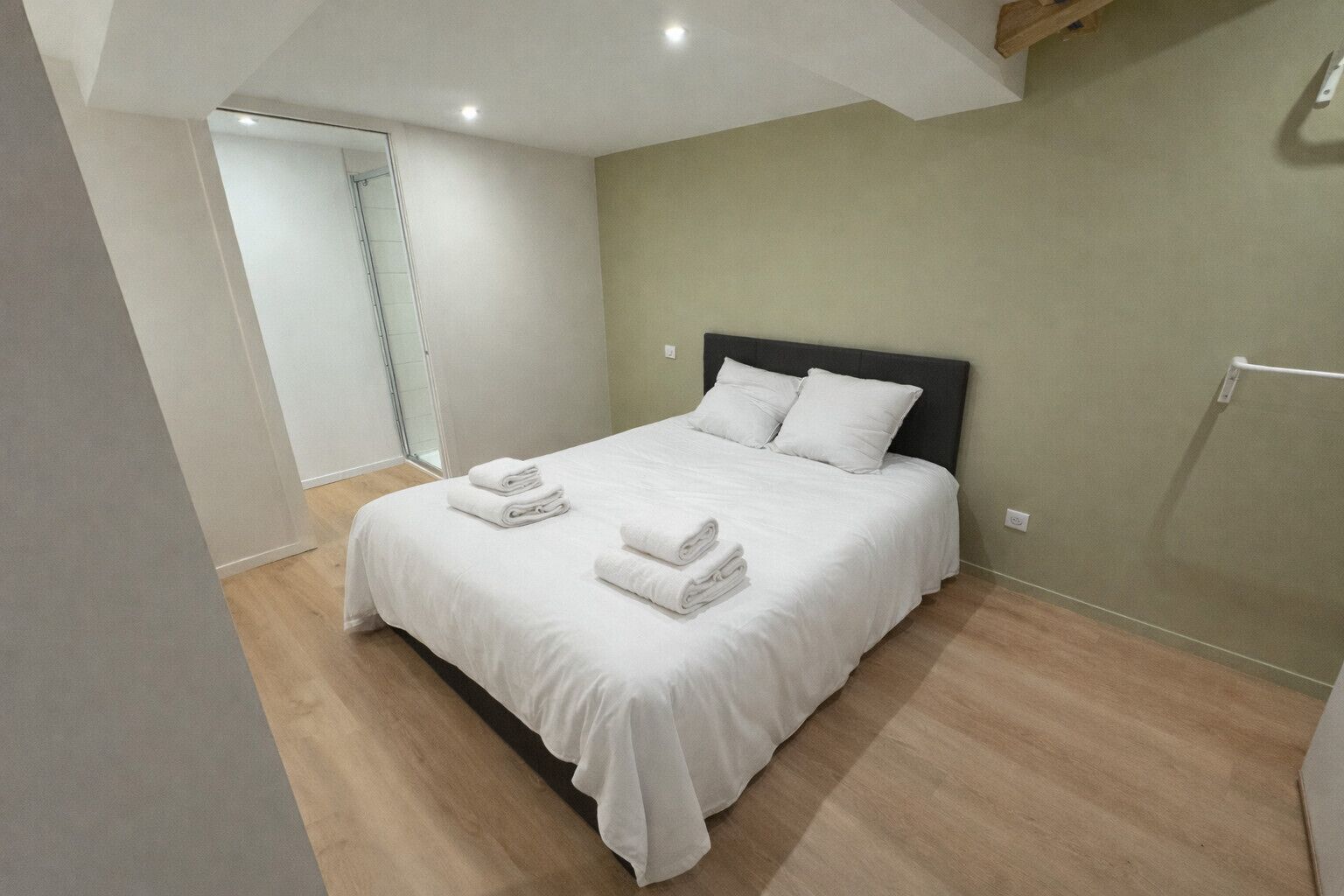 A bedroom with a bed, white bedding, and towels.