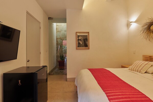 A bedroom with a bed, a TV, a desk, and a door. - Casona Soledad - Olga (Oaxaca)
