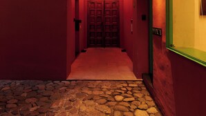 A corridor with a stone floor, a wooden ceiling, and a red wall.