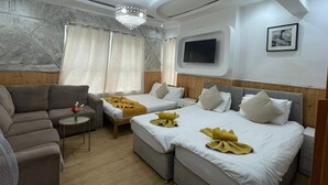 A hotel room with two beds, a sofa, a small table, and a TV mounted on the wall. - Deluxe Room with attached bathroom in Blackpool-Families and couples only (Blackpool)