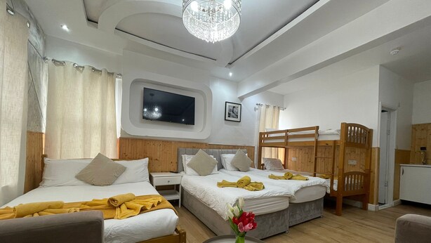 A hotel room with two beds, a TV, a small table with a vase of flowers, and a bunk bed. - Deluxe Room with attached bathroom in Blackpool-Families and couples only (Blackpool)