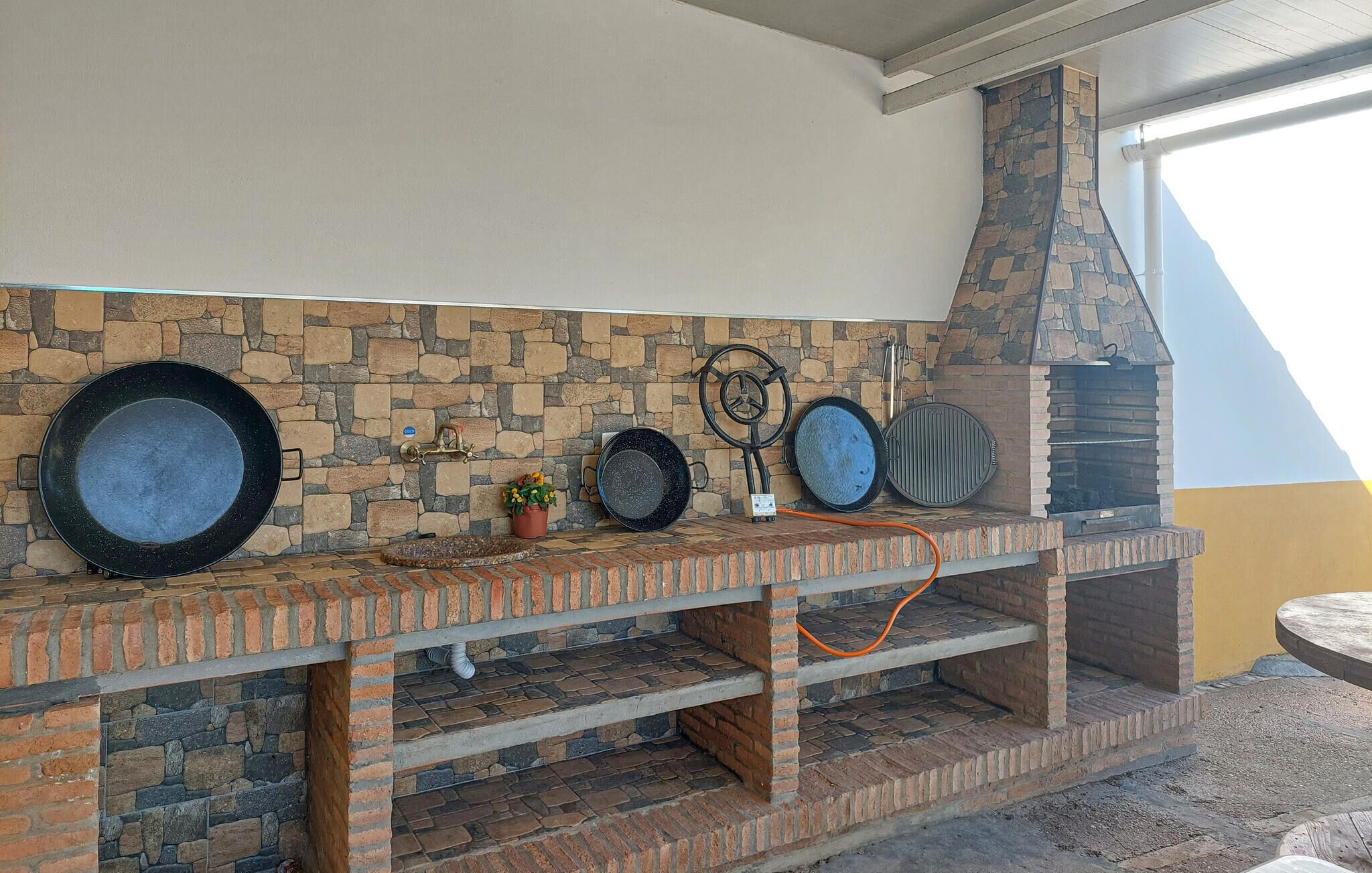 A stone-tiled backsplash with a built-in grill and a brick oven.
