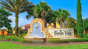 A sign with "Bella Vida" written on it, surrounded by palm trees and a well-maintained garden. - Near Disney~Private Patio~Family~Bella Vida Resort (Kissimmee)