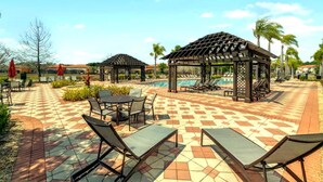 A poolside area with lounge chairs, a gazebo, and a tiled patio. - Near Disney~Private Patio~Family~Bella Vida Resort (Kissimmee)